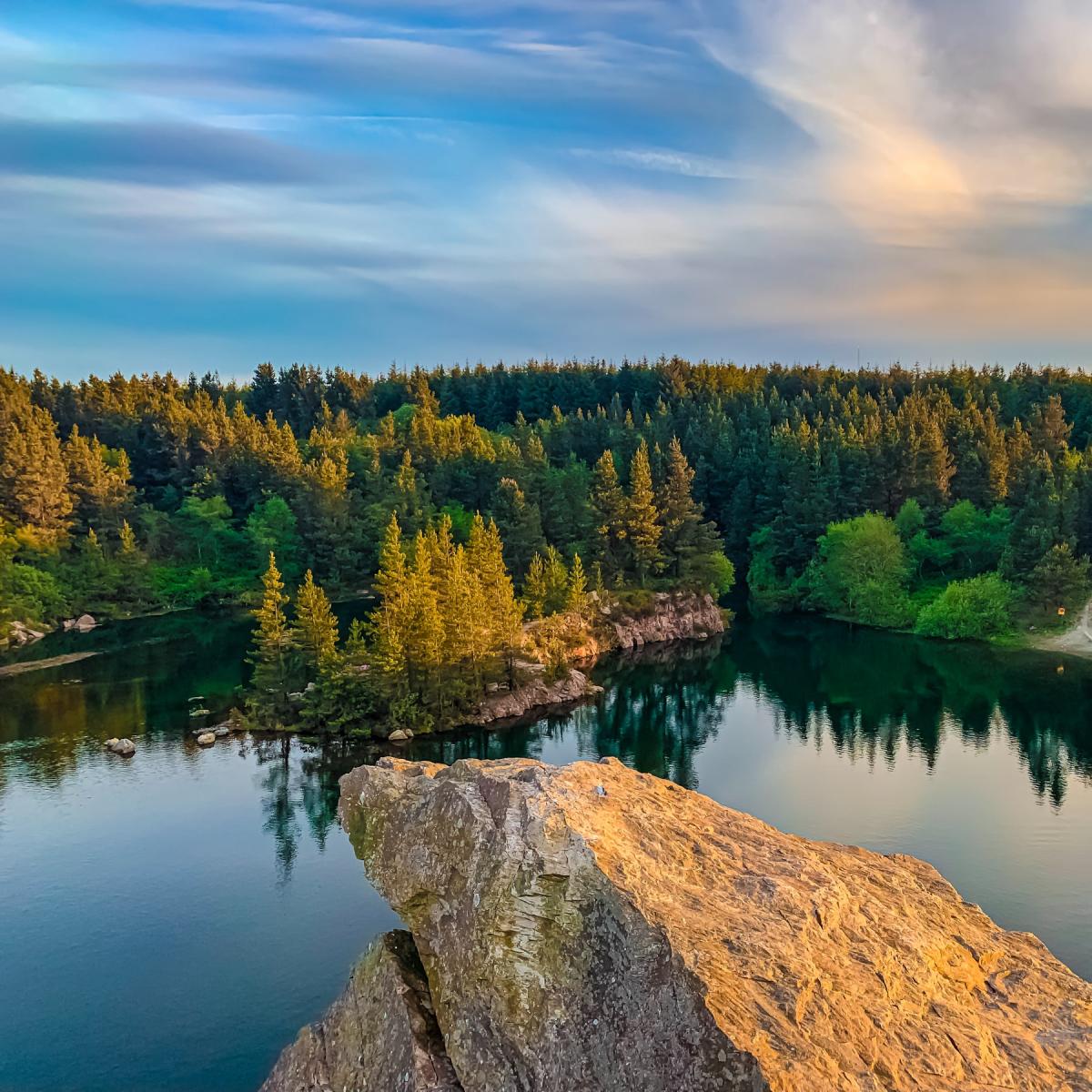 High view of forest across a lake with a rocky point in the foreground